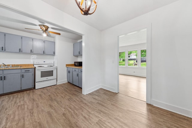 kitchen featuring gray cabinets, white electric stove, black microwave, a sink, and light wood-type flooring