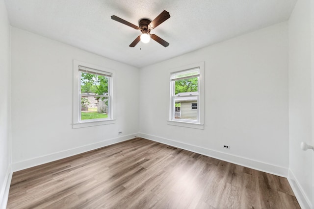 empty room with baseboards, visible vents, wood finished floors, and ceiling fan