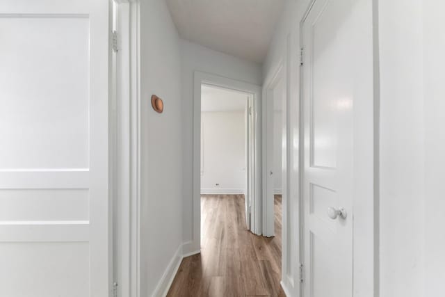 corridor featuring wood finished floors and baseboards