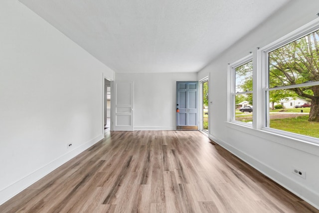 unfurnished living room with baseboards and light wood-style flooring