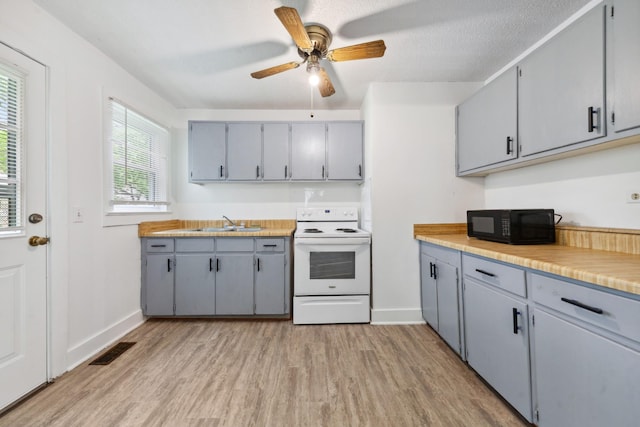 kitchen featuring a sink, black microwave, white range with electric stovetop, visible vents, and gray cabinetry