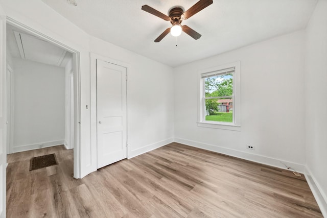 unfurnished bedroom with ceiling fan, a closet, baseboards, attic access, and light wood finished floors