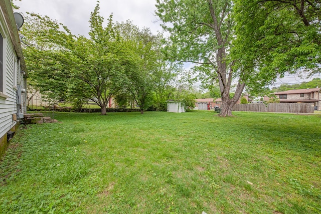 view of yard with fence, a storage unit, and an outdoor structure