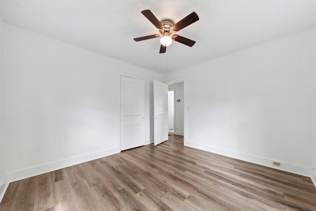 unfurnished room with wood finished floors, ceiling fan, and baseboards