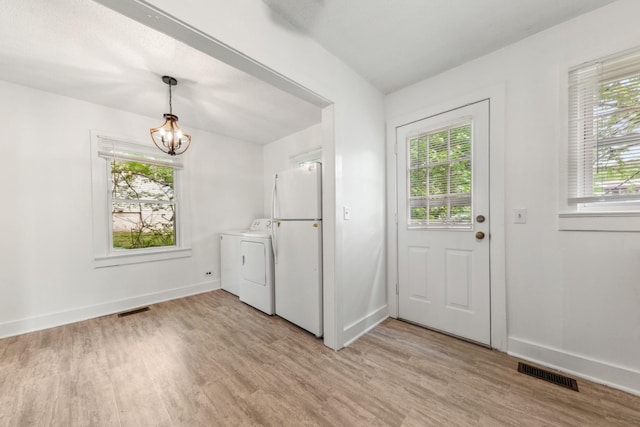 laundry area with visible vents, washing machine and clothes dryer, light wood-style flooring, and laundry area