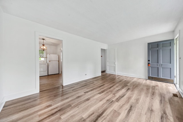 unfurnished living room featuring wood finished floors, visible vents, a chandelier, and baseboards