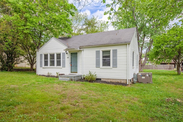 view of front of property featuring a front yard, a shingled roof, and fence