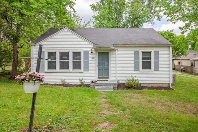view of front of house featuring a shingled roof and a front yard