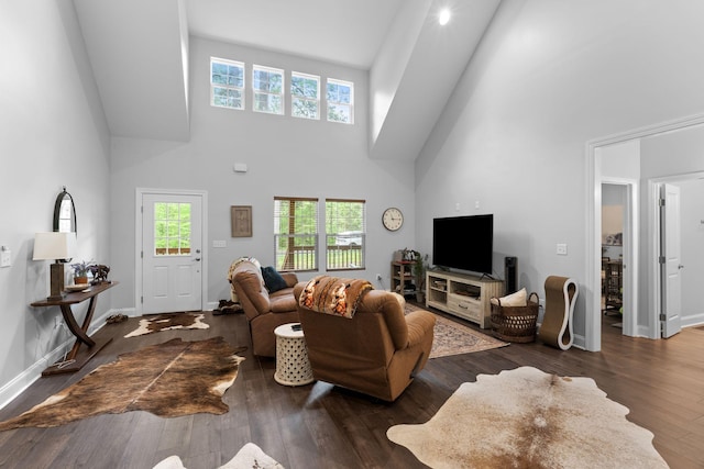 living room featuring a high ceiling, baseboards, wood finished floors, and a healthy amount of sunlight