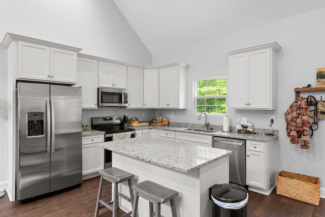 kitchen with a breakfast bar area, a sink, stainless steel appliances, a kitchen island, and dark wood finished floors