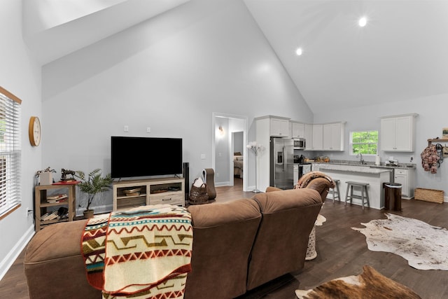 living room featuring dark wood-type flooring, high vaulted ceiling, and baseboards