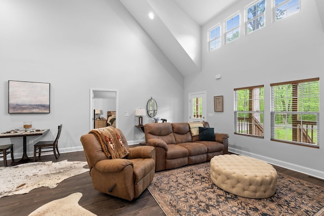 living room with baseboards, visible vents, dark wood finished floors, and a towering ceiling