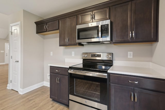 kitchen with dark brown cabinetry, stainless steel appliances, light wood finished floors, and baseboards