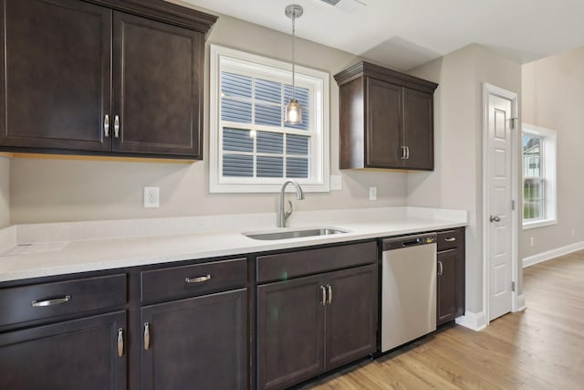 kitchen featuring light wood-style flooring, light countertops, dark brown cabinets, dishwasher, and a sink