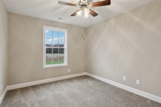 carpeted spare room featuring baseboards, visible vents, and ceiling fan