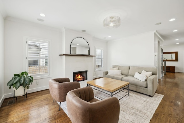 living room featuring crown molding, wood finished floors, a tiled fireplace, and a wealth of natural light