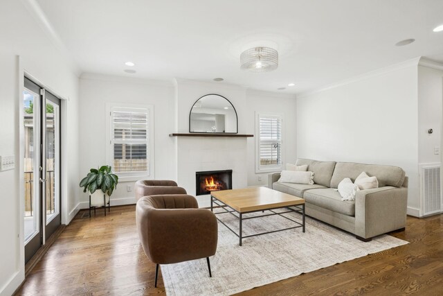 living area with visible vents, a wealth of natural light, a tile fireplace, and crown molding