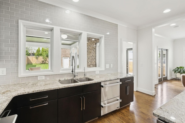 kitchen featuring dark wood-type flooring, a healthy amount of sunlight, crown molding, and a sink