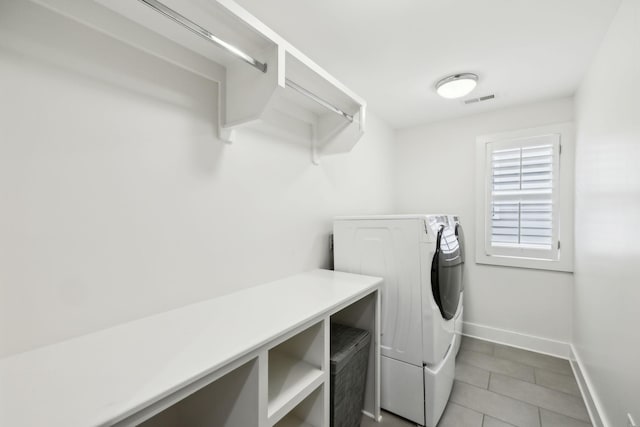 washroom featuring washing machine and clothes dryer, light tile patterned flooring, laundry area, visible vents, and baseboards