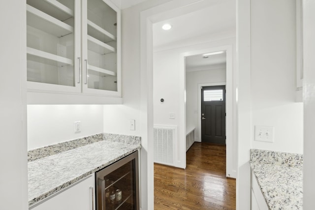 bar with crown molding, beverage cooler, visible vents, a bar, and dark wood-style floors