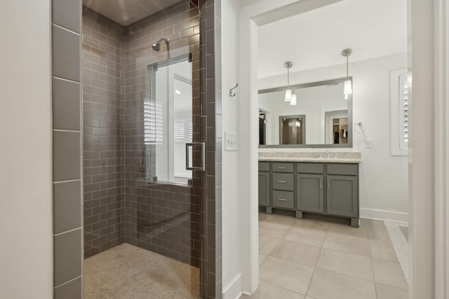 full bathroom featuring tile patterned flooring, tiled shower, vanity, and baseboards