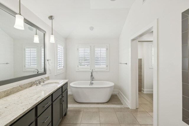 full bath featuring vanity, tile patterned flooring, a soaking tub, and baseboards