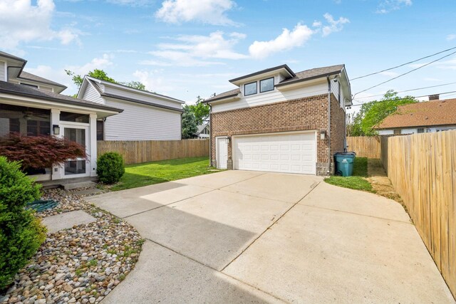 view of property exterior featuring a sunroom, a yard, driveway, brick siding, and fence
