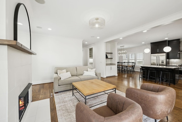 living area featuring a tiled fireplace, recessed lighting, ornamental molding, and dark wood-style flooring