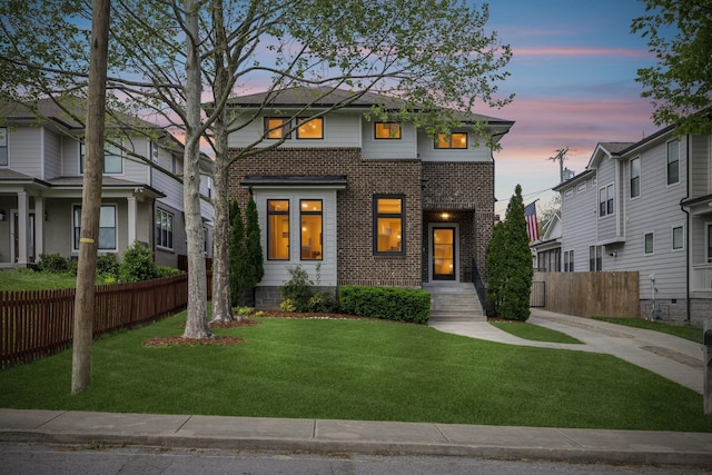 view of front of property featuring brick siding, fence, and a front lawn