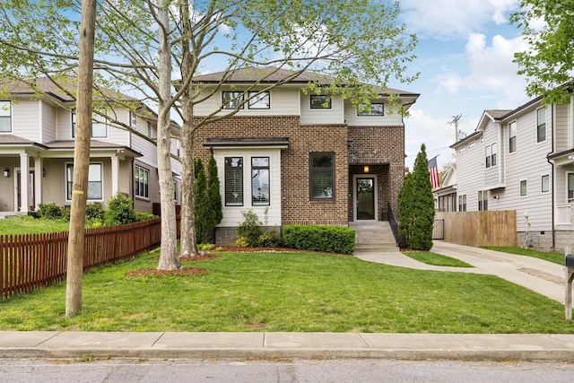 view of front facade featuring a front yard, fence, and brick siding