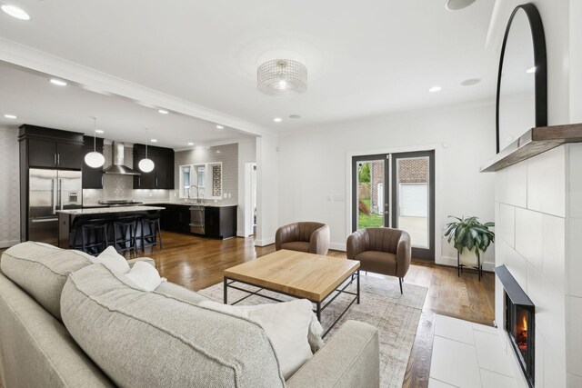 living area featuring wood finished floors, ornamental molding, and a fireplace