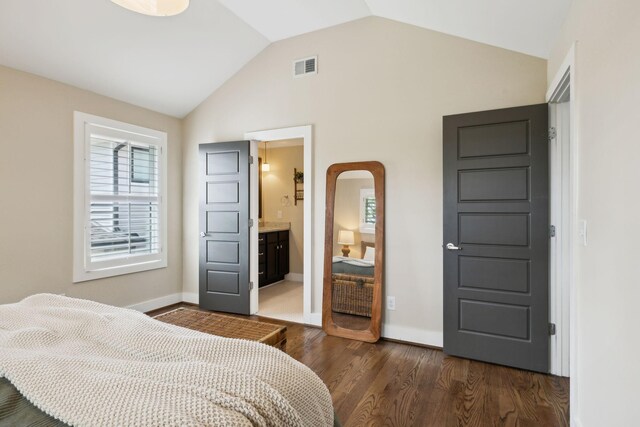 bedroom featuring lofted ceiling, connected bathroom, visible vents, baseboards, and dark wood-type flooring
