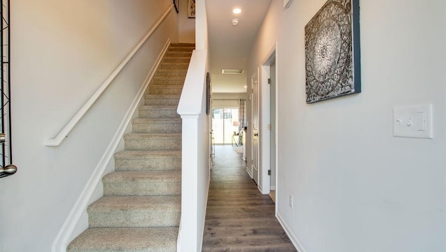 staircase with visible vents, wood finished floors, and baseboards