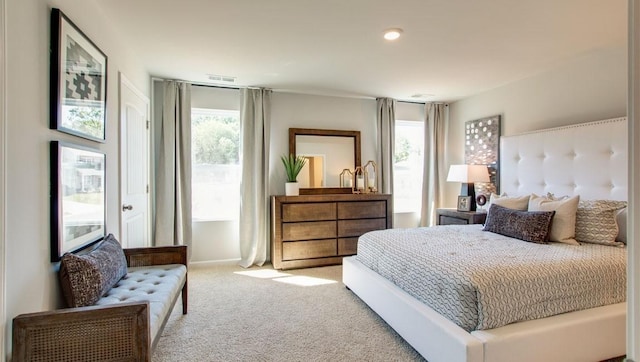 carpeted bedroom with visible vents and multiple windows