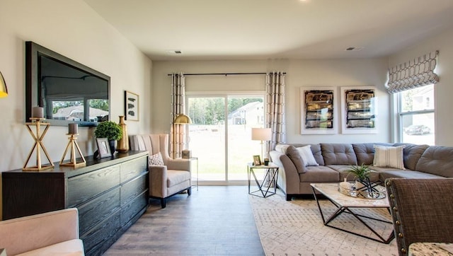 living room featuring visible vents, wood finished floors, and a healthy amount of sunlight