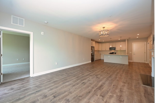 141 Saundersville Rd Unit 1305, Hendersonville, TN 37075 - unfurnished living room with an inviting chandelier, visible vents, wood finished floors, and baseboards