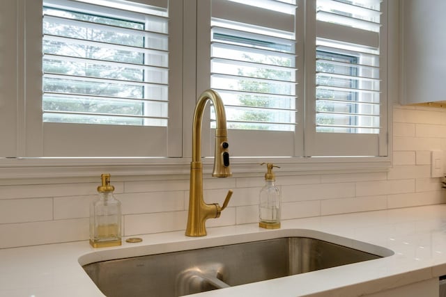 interior details with light stone counters, a sink, and backsplash