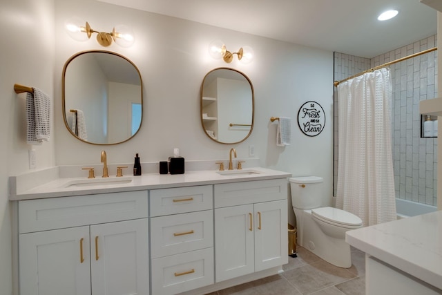 full bathroom with toilet, double vanity, a sink, and tile patterned floors