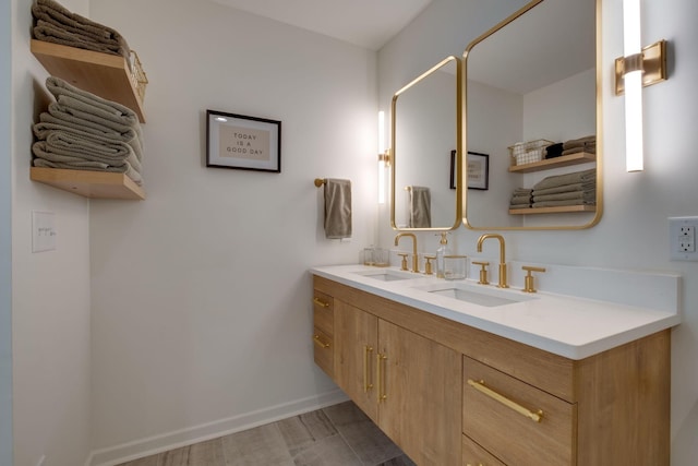 bathroom with baseboards, double vanity, and a sink