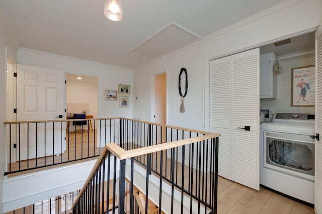 laundry area featuring attic access, cabinet space, light wood-type flooring, crown molding, and washer / clothes dryer