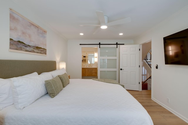 bedroom with a barn door, light wood-style flooring, crown molding, and recessed lighting