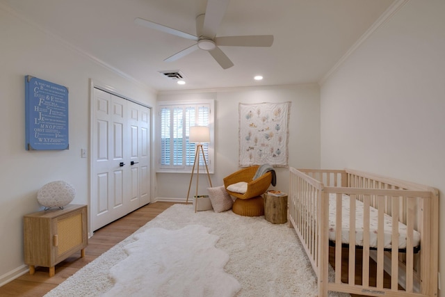 bedroom featuring wood finished floors, visible vents, crown molding, and baseboards