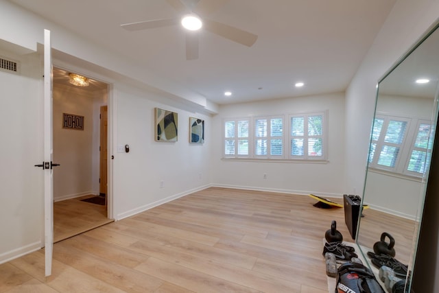 workout room featuring a ceiling fan, baseboards, and light wood-style floors