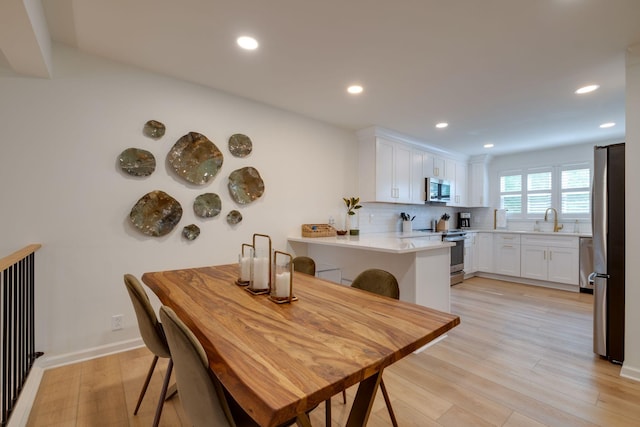 dining room featuring recessed lighting, baseboards, and light wood-style floors
