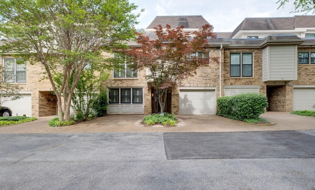 multi unit property featuring brick siding, a shingled roof, driveway, and an attached garage