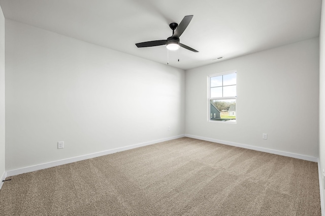 carpeted empty room featuring baseboards, visible vents, and a ceiling fan