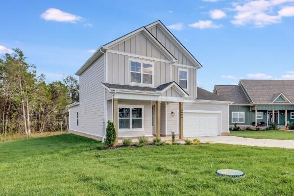view of front facade featuring board and batten siding, a front lawn, driveway, and a porch