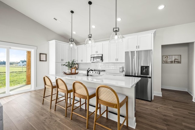 kitchen featuring appliances with stainless steel finishes, dark wood-type flooring, tasteful backsplash, and vaulted ceiling
