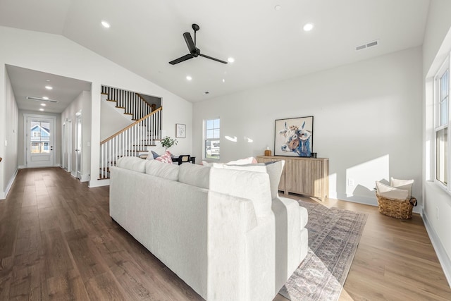 living area with lofted ceiling, stairs, a ceiling fan, visible vents, and wood finished floors