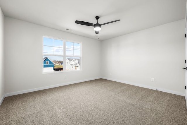 carpeted spare room with visible vents, a ceiling fan, and baseboards